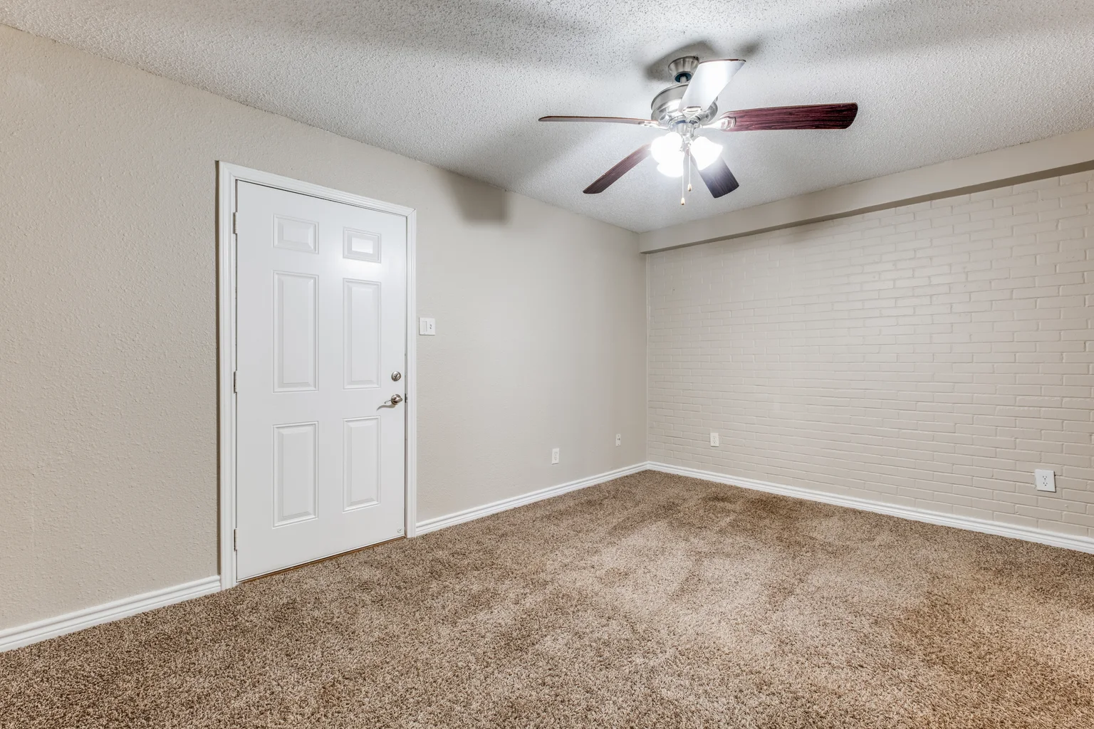 A carpeted bedroom with a ceiling fan and a white door.