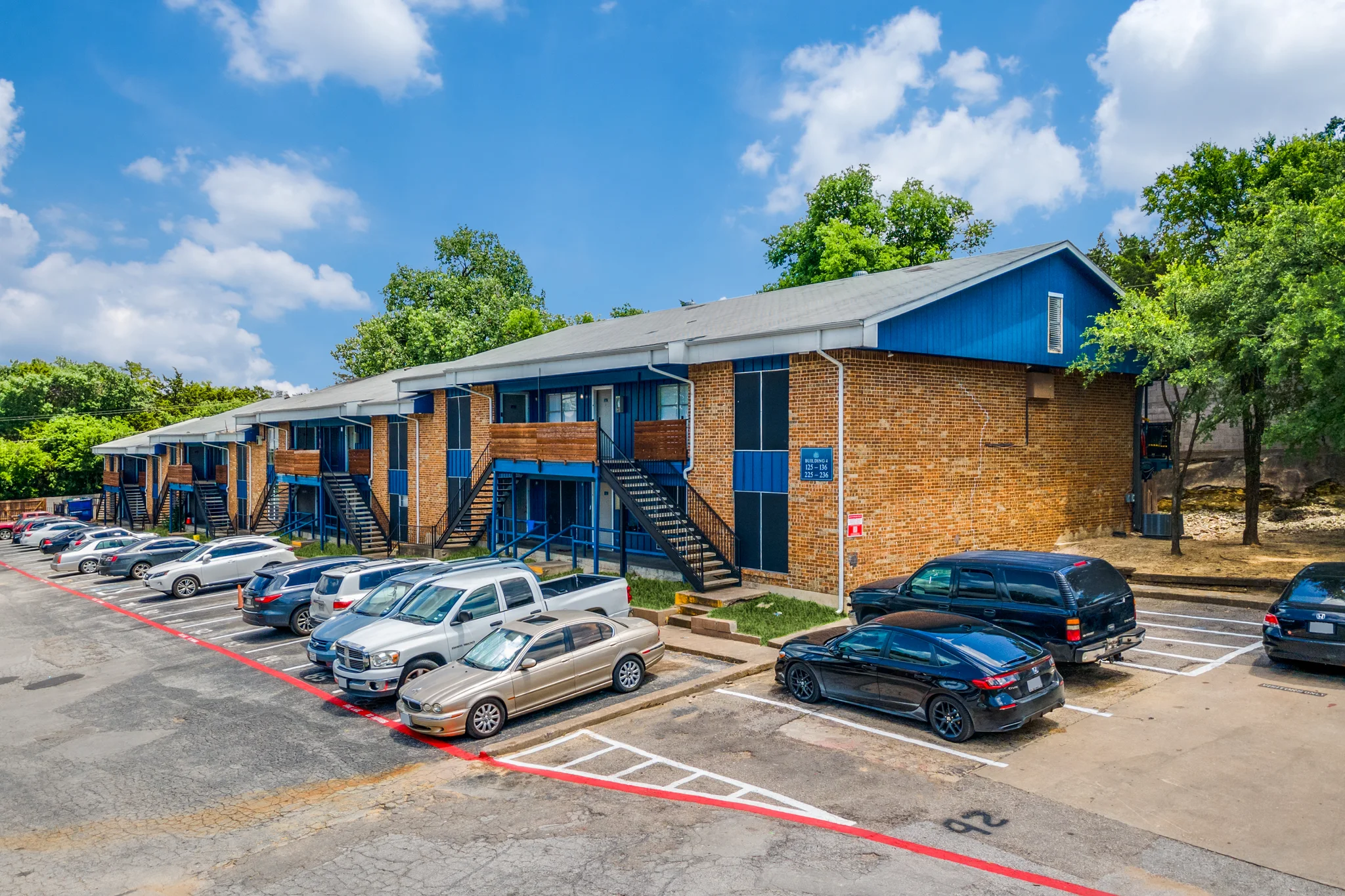 A two story brick building with blue panelled infills, seen across the parking court.
