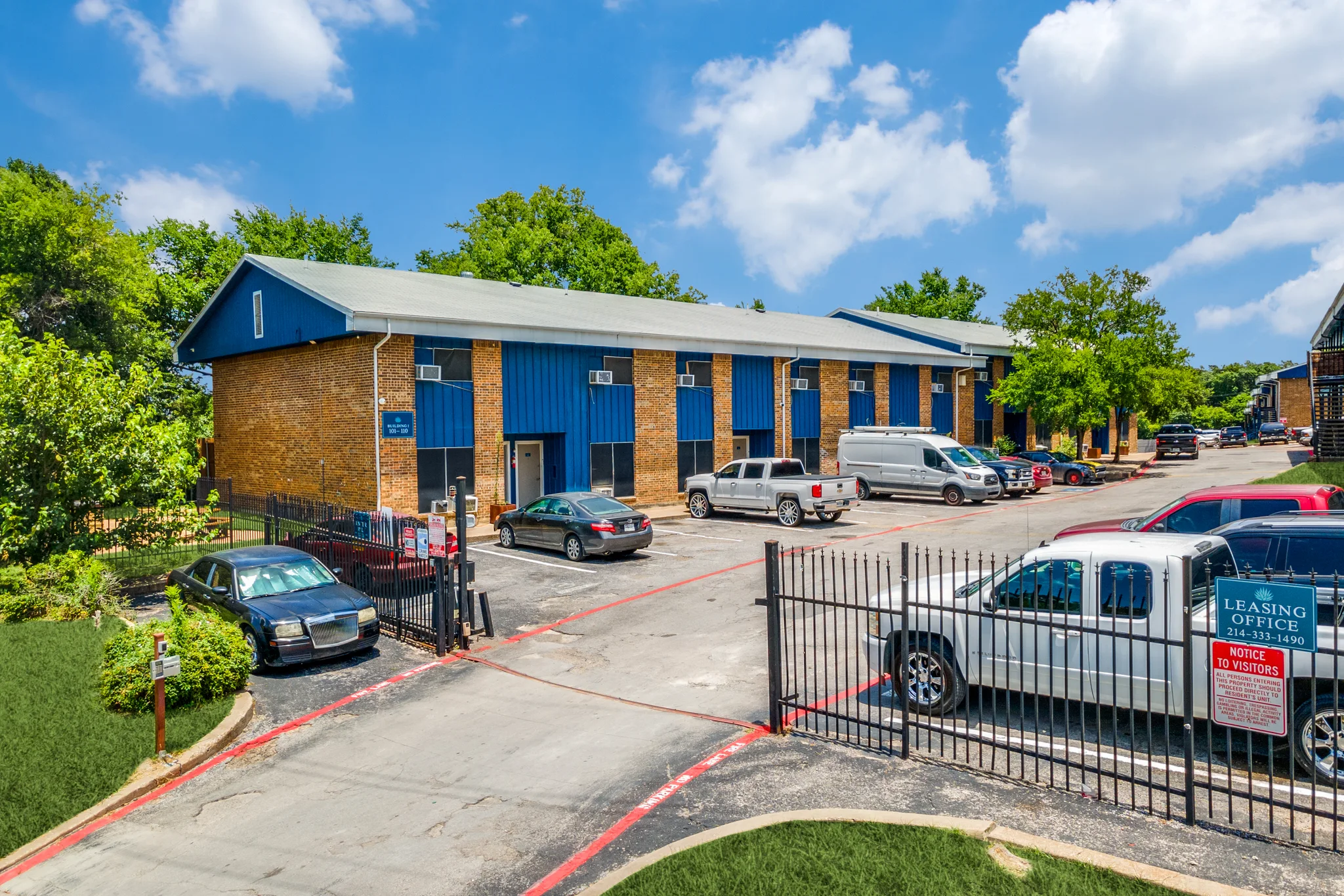 The gated entry, with brick buildings and blue metal roofs beyond it.