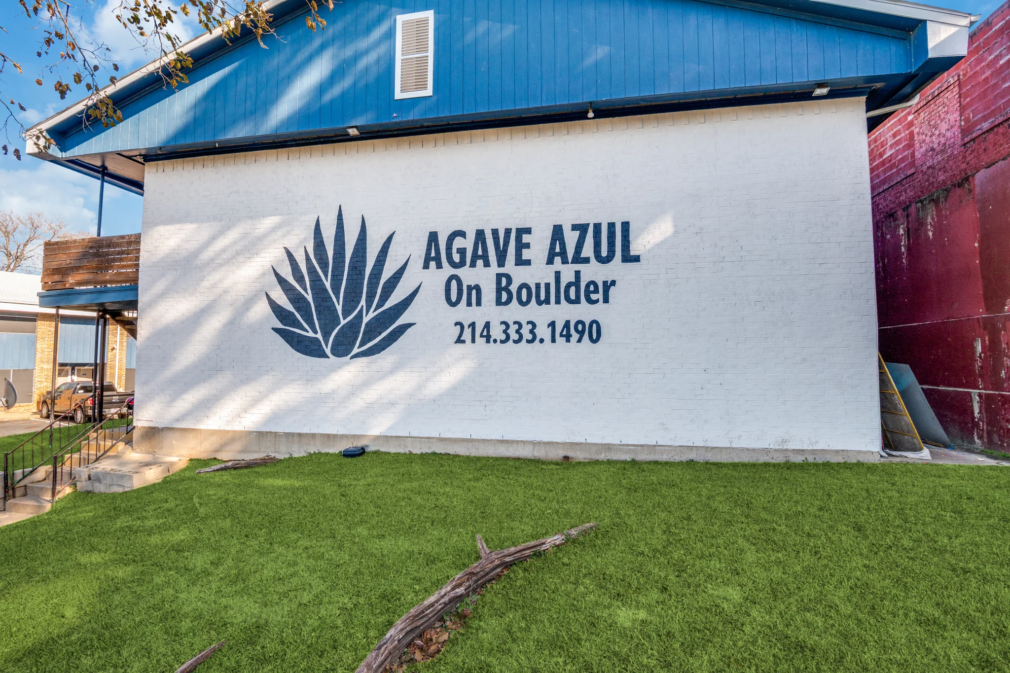 The property name and the agave mark painted on a white brick wall, above the lawn.