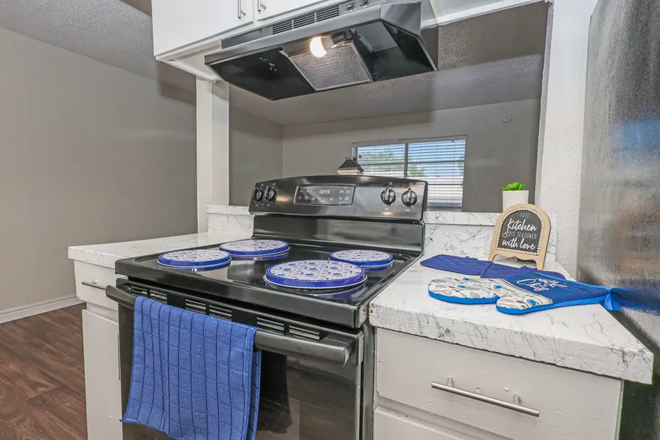 A kitchen with an extractor hood over the range and white cabinets either side.