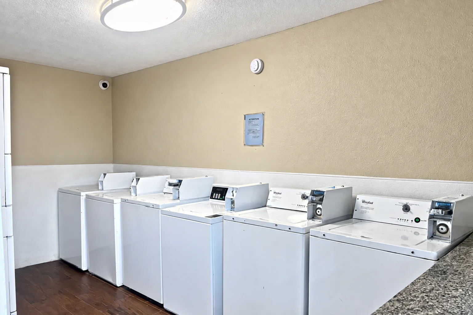 The shared laundry room, a row of coin operated washers and dryers along the wall.