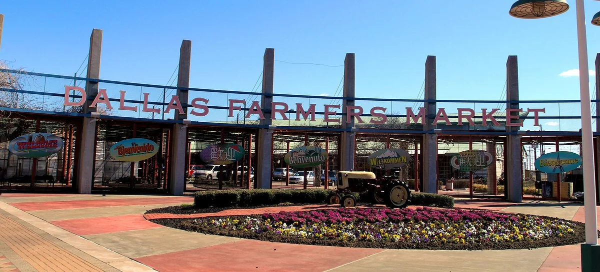 The Dallas Farmers Market sign over the open-air market shed, with a vintage tractor out front.