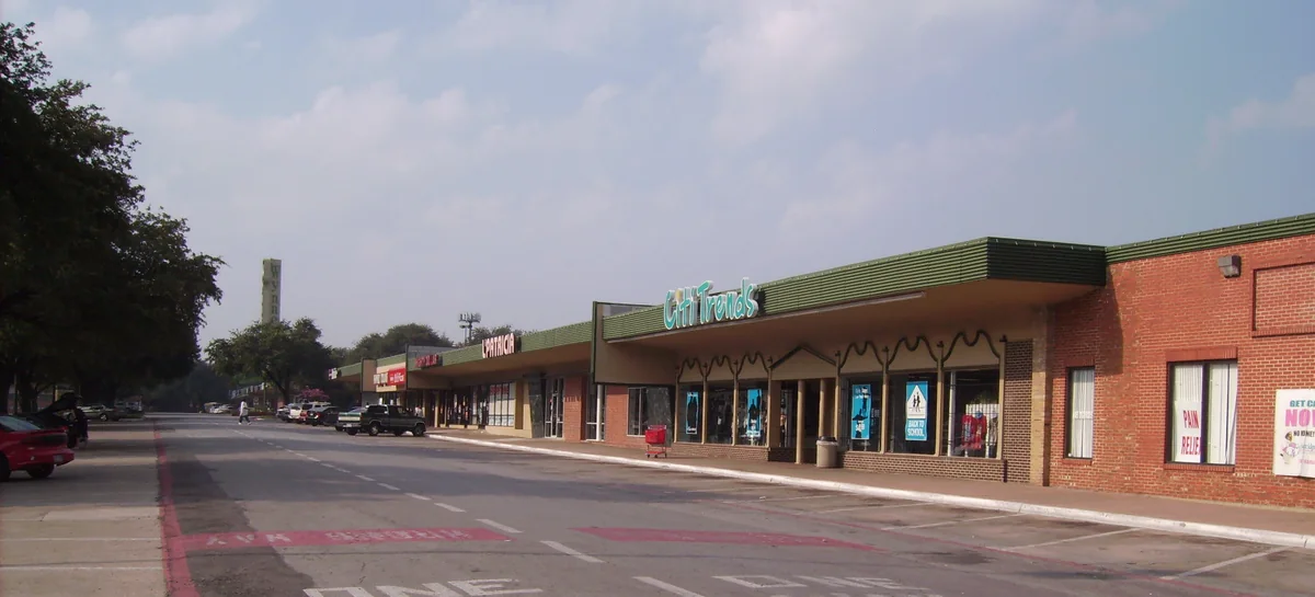 Storefronts under a green awning along the brick frontage of Wynnewood Village.