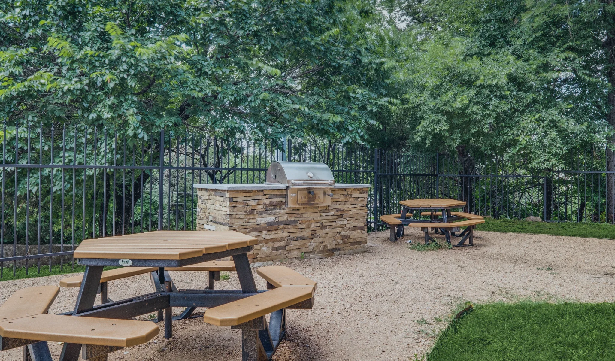 The grill station and wooden picnic tables under the trees.